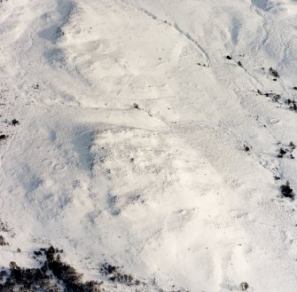 Oblique aerial view of Garbeg centred on the remains of hut-circles, a field-system, small cairns and rig, taken from the W.