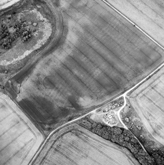Oblique aerial view centred on the cropmarks of the possible enclosure, roundhouse, rig and pits with cottages adjacent, taken from the S.
