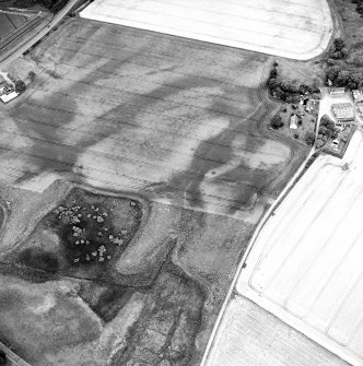 Oblique aerial view centred on the cropmarks of the possible pit-defined enclosure, pits, linear cropmarks and promontory fort with church, mausoleum and cemetery adjacent, taken from the W.