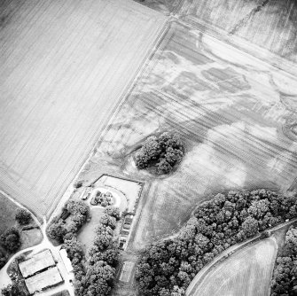 Oblique aerial view centred on the remains of the cairn with Arcan Mains adjacent, taken from the SW.