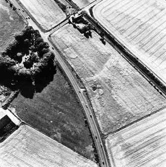 Culloden, oblique aerial view, taken from the E, centred on a pit-alignment and other cropmarks and the remains of a chambered cairn. Culloden railway station is visible in the top centre half of the photograph.