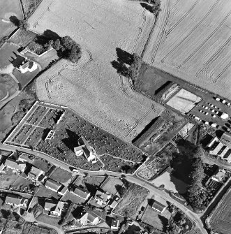 Oblique aerial view centred on the church, churchyard and excavation, taken from the WNW.