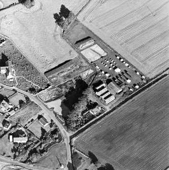 Oblique aerial view centred on the excavation with church and churchyard adjacent, taken from the W.