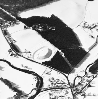 Oblique aerial view of Doune of Invernochty centred on the remains of the motte, chapel, castle, building and observation post with Bellabeg adjacent, taken from the ENE.