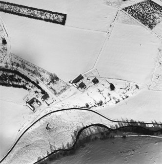 Oblique aerial view of Badenyon centred on the site of the castle, the remains of a limekiln, and a farmsteading, taken from the SSW.