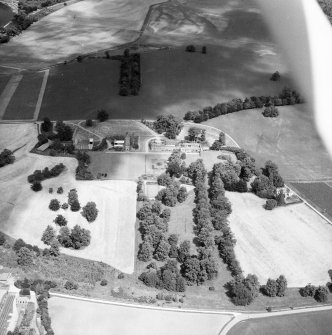 Oblique aerial view from South of Gordon Castle estate (after demolitions), including house, tower, home farm, laundry cottages, Wilderness and cropmarks.