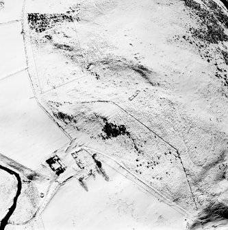 Oblique aerial view of Cairnbeg Hill centred on the remains of a farmhouse, farmsteading, limekiln, and buildings with the remains of a quarry, kiln, enclosure, ring-ditch houses, small cairns and a cairn adjacent, taken from the ENE.