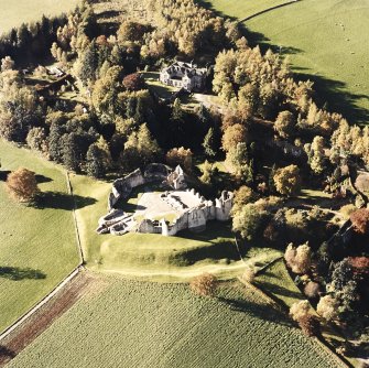 Oblique aerial view of Kildrummy castle centred on the remains of the castle, with hotel adjacent taken from the E.