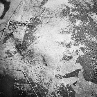 Oblique aerial view centred on the remains of the cairn and small cairns with buildings adjacent, taken from the ENE.