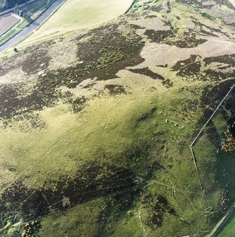 Oblique aerial view centred on the remains of the cairn and small cairns with buildings adjacent, taken from the SW.