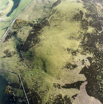 Oblique aerial view centred on the remains of the cairn and small cairns with buildings adjacent, taken from the NE.