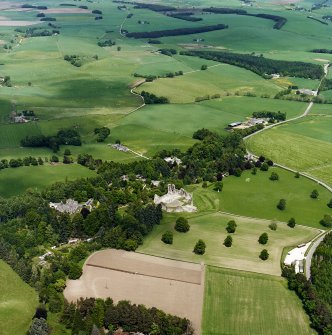 Oblique aerial view centred on the remains of the castle with hotel, farmhouse and farmsteading adjacent, taken from the SW.