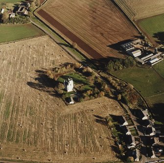 Oblique aerial view of Leslie Castle centred on the castle with farmhouses adjacent, taken from the NW.