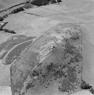Oblique aerial view of Dunnideer centred on the remains of a fort and tower-house, taken from the ENE.