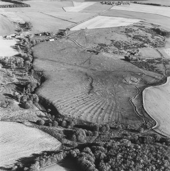 Oblique aerial view of Wardhouse Home farm centred on the remains of rig, small cairns and farmstead with cairns, field system, quarry and cottage adjacent, taken from the NW.