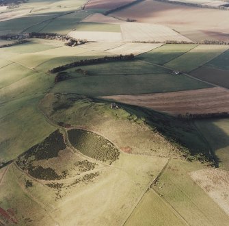 Oblique aerial view of Dunnideer centred on the remains of the fort and tower-house, taken from the S.