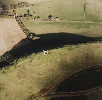 Oblique aerial view of Dunnideer centred on the remains of the fort and tower-house, taken from the SW.
