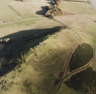 Oblique aerial view of Dunnideer centred on the remains of the fort and tower-house, taken from the W.