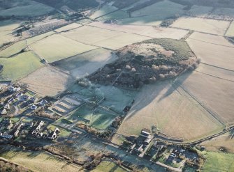 Oblique aerial view centred on the visitor centre, experimental archaeology site and the remains of the enclosure with the village adjacent, taken from the NNW.