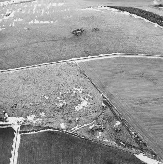 Oblique aerial view centred on the remains of the ring-cairn with rig adjacent, taken from the N.