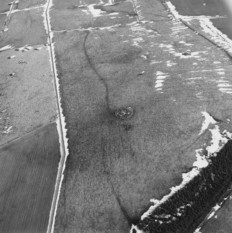Oblique aerial view centred on the remains of the ring-cairn with rig adjacent, taken from the W.