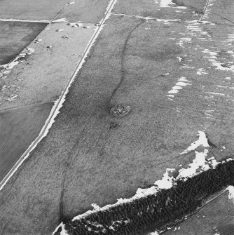 Oblique aerial view centred on the remains of the ring-cairn with rig adjacent, taken from the WSW.