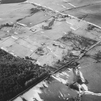 Oblique aerial view of the remains of rig, hut-circle, small cairns and quarries taken from the NE.