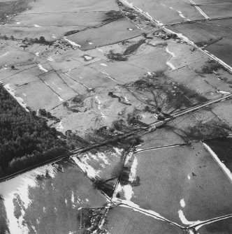 Oblique aerial view of the remains of rig, hut-circle, small cairns and quarries taken from the NE.