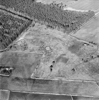 Oblique aerial view centred on the remains of the hut-circle, buildings and small cairns, taken from the SSW.