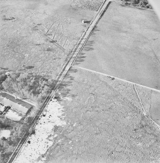 Oblique aerial view centred on the remains of the hut-circle, buildings and small cairns, taken from the ESE.