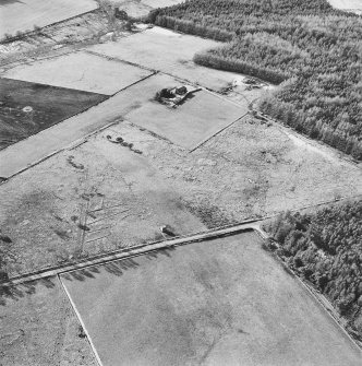 Oblique aerial view centred on the remains of the hut-circle, buildings and small cairns, taken from the ENE.