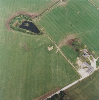 Oblique aerial view centred on the ruins of the tower-house with the farmsteading adjacent, taken from the S.