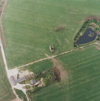Oblique aerial view centred on the ruins of the tower-house with the farmsteading adjacent, taken from the ENE.