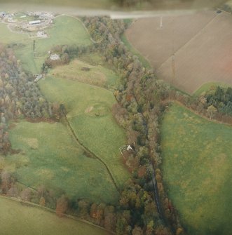 Oblique aerial view centred on the remains of the motte with the church, burial-ground and manse adjacent, taken from the SE.