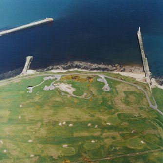 Oblique aerial view centred on the remains of the coastal battery with breakwaters adjacent, taken from the S.