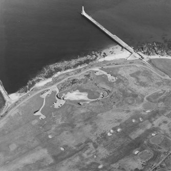 Oblique aerial view centred on the remains of the coastal battery with breakwaters adjacent, taken from the SSW.