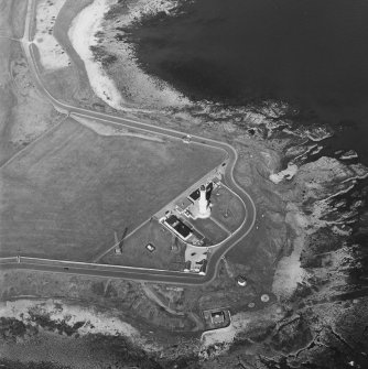 Oblique aerial view centred on the lighthouse with sewage works adjacent, taken from the SE.