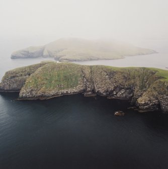 General oblique aerial view of the lighthouse with the island of Mingulay and those to the N in the background, taken from the S.