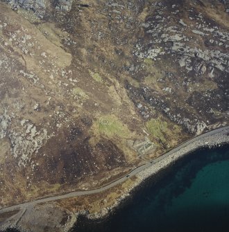 Oblique aerial view centred on the remains of the wheelhouse and blackhouse with the remains of the building and hut-circle adjacent, taken from the S.