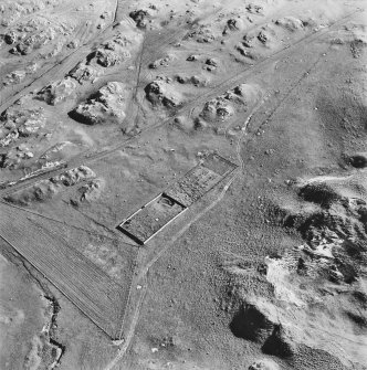 Oblique aerial view of Killunaig church centred on the remains of a church and a cemetery, taken from the NNW.