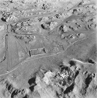 Oblique aerial view of Killunaig church centred on the remains of a church and a cemetery, taken from the NW.