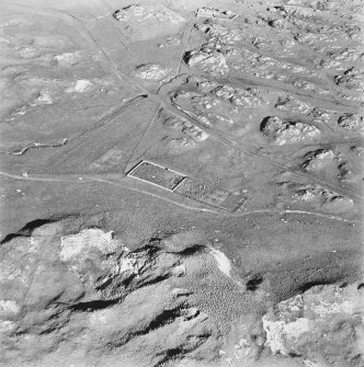 Oblique aerial view of Killunaig church centred on the remains of a church and a cemetery, taken from the WSW.