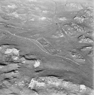 Oblique aerial view of Killunaig church centred on the remains of a church and a cemetery, taken from the SW.