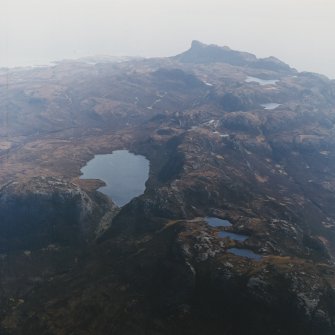 General oblique aerial view of the southwest side of Eigg with the remains of An Sgurr fort in the distance, taken from the NNW.