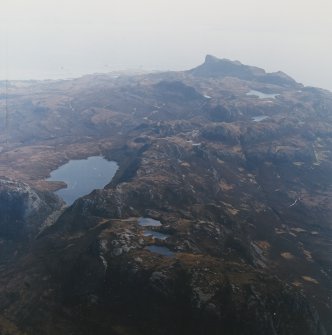 General oblique aerial view of the southwest side of Eigg with the remains of An Sgurr fort in the distance, taken from the NW.