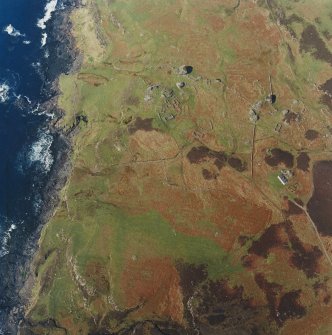 Oblique aerial view centred on the remains of the township, field-system, rig, lazy-beds, dun and shepherd¿s bothy, taken from the SE.