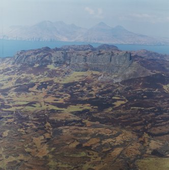 Oblique aerial view centred on the remains of the An Sgurr fort with Rum in the background, taken from the SE.