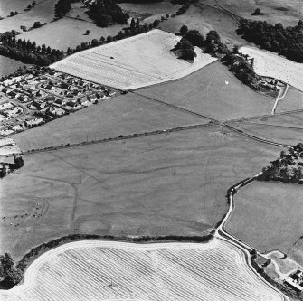 Dalginross, oblique aerial view, taken from the WNW, centred on the cropmarks of the Roman Temporary Camp. The Roman Fort is visible in the bottom left-hand corner of the photograph.