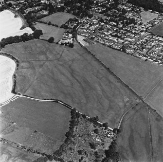 Dalginross, oblique aerial view, taken from the SSW, centred on the cropmarks of the Roman Temporary Camp. The Roman Fort is visible in the top left-hand corner of the photograph.