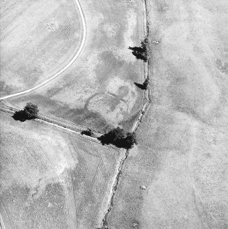 Monzie, oblique aerial view, taken from the WNW, centred on the cropmarks of a palisaded settlement. Cropmarks of a barrow are visible in the top half of the photograph.
